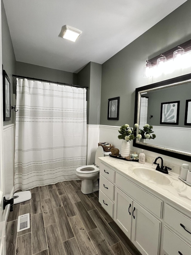 bathroom featuring vanity, visible vents, wainscoting, toilet, and wood tiled floor