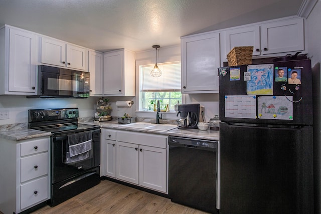 kitchen featuring white cabinets, a sink, light countertops, wood finished floors, and black appliances