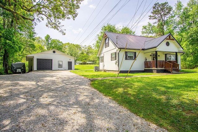 view of front of home featuring a front lawn, central AC, gravel driveway, an outbuilding, and a detached garage