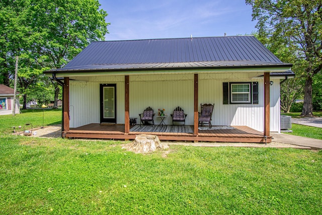 rear view of house featuring a lawn, central AC unit, covered porch, and metal roof
