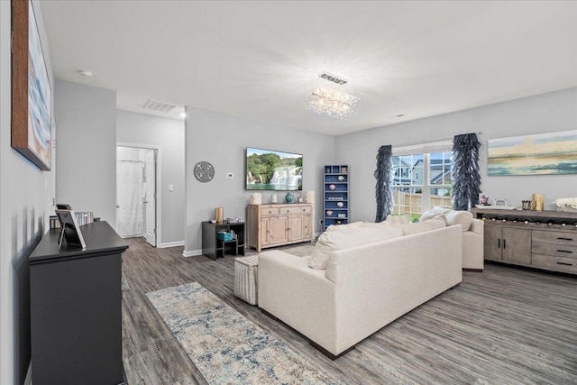 living area with baseboards, visible vents, wood finished floors, and an inviting chandelier