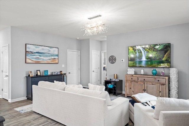 living area with baseboards, an inviting chandelier, wood finished floors, and visible vents