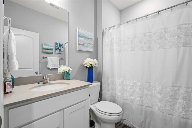 bathroom with vanity, toilet, and visible vents