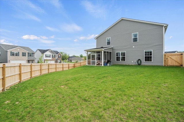 back of property with a sunroom, a fenced backyard, a lawn, and a residential view