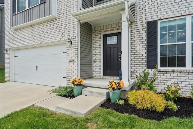 doorway to property with brick siding, an attached garage, and driveway