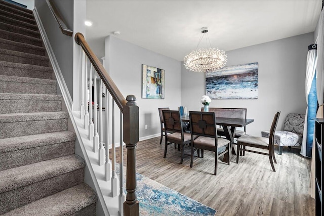 dining area with an inviting chandelier, baseboards, stairs, and wood finished floors
