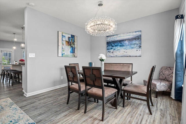 dining space featuring baseboards, an inviting chandelier, and wood finished floors