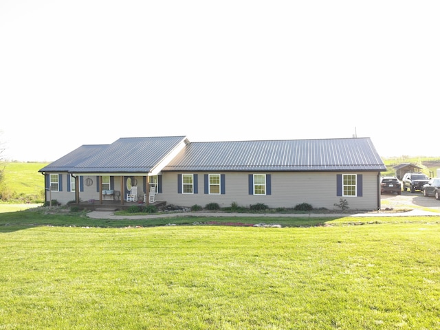 ranch-style home featuring metal roof, a porch, and a front lawn