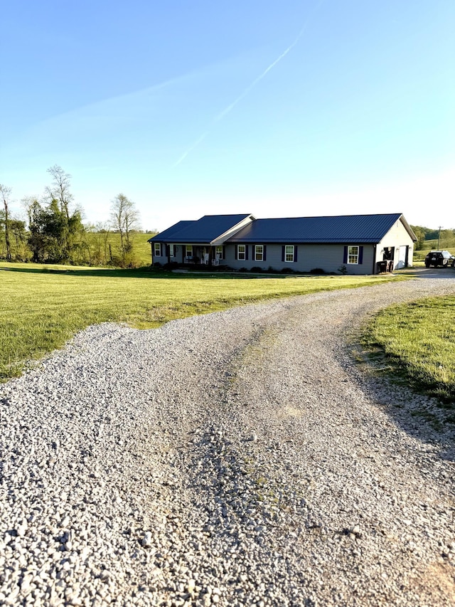 view of front of property with metal roof, gravel driveway, and a front yard