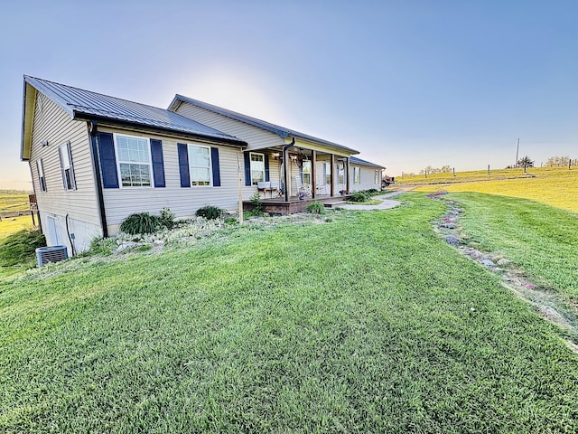 view of front facade with a standing seam roof, covered porch, metal roof, and a front yard