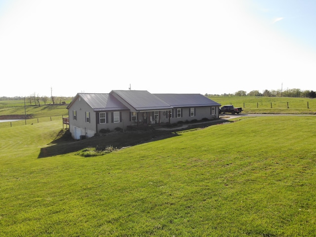 exterior space featuring a garage, a rural view, metal roof, and a front yard
