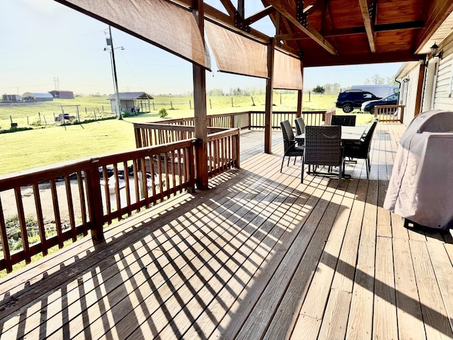 wooden deck featuring a lawn, a rural view, and outdoor dining area