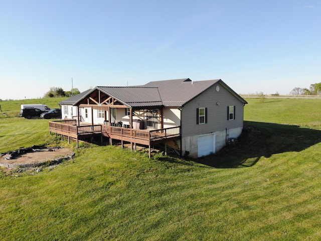 back of property with a lawn, metal roof, a deck, and a garage