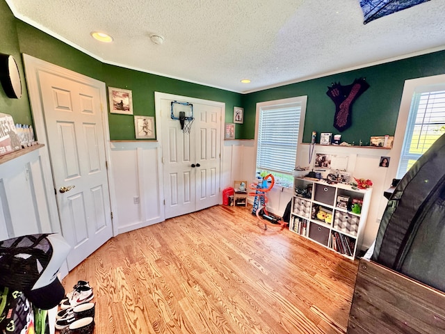 game room featuring recessed lighting, a textured ceiling, wainscoting, and wood finished floors