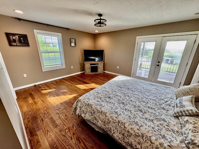 bedroom featuring wood finished floors, baseboards, access to outside, a textured ceiling, and french doors