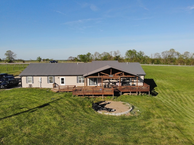 back of property with a lawn, a deck, and metal roof