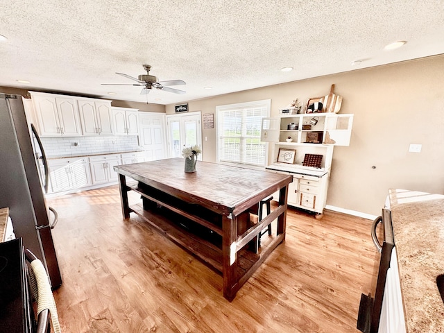 kitchen featuring freestanding refrigerator, a textured ceiling, and light wood finished floors