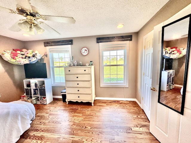 bedroom featuring multiple windows, a textured ceiling, and wood finished floors