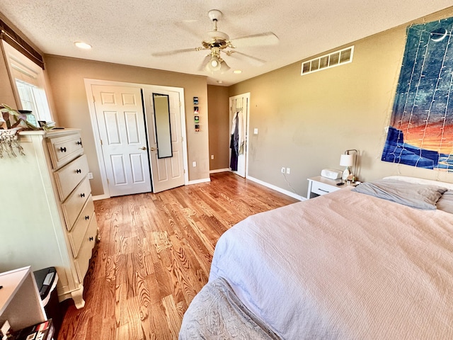 bedroom with visible vents, baseboards, ceiling fan, a textured ceiling, and light wood-style flooring