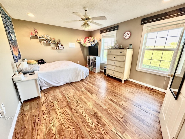 bedroom with ceiling fan, a textured ceiling, recessed lighting, baseboards, and wood finished floors