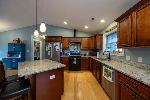 kitchen featuring visible vents, light wood-style floors, a breakfast bar area, a sink, and black appliances