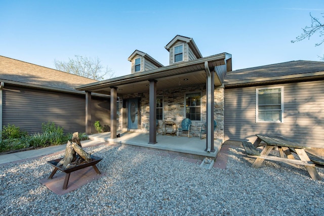rear view of house featuring covered porch and stone siding