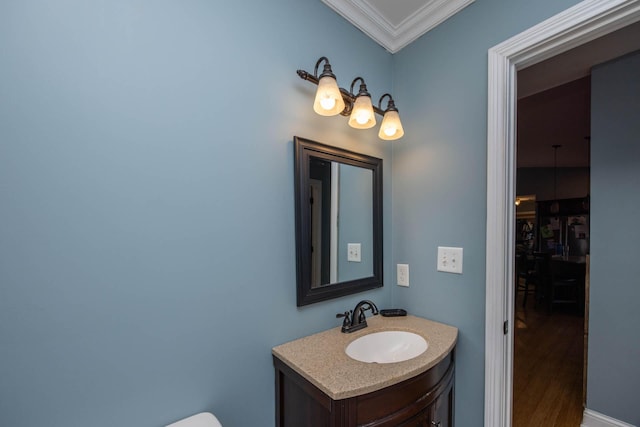 half bathroom featuring crown molding, vanity, and wood finished floors