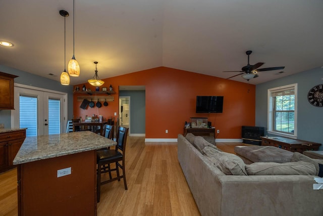 living room with baseboards, ceiling fan, light wood-style flooring, and lofted ceiling