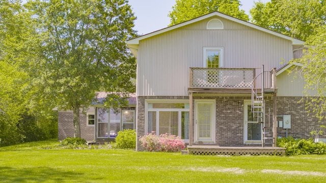 rear view of property with a lawn, a wooden deck, a balcony, and brick siding