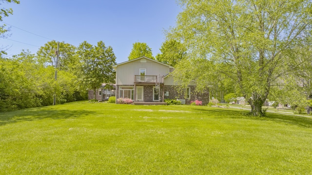back of property with a yard, brick siding, and a balcony
