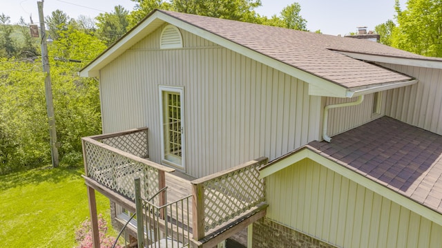 view of home's exterior featuring a yard, stairway, a wooden deck, and roof with shingles