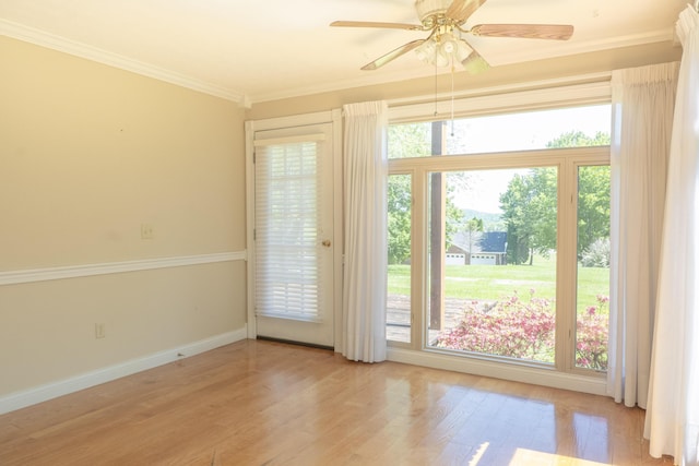 doorway with crown molding, baseboards, a ceiling fan, and wood finished floors
