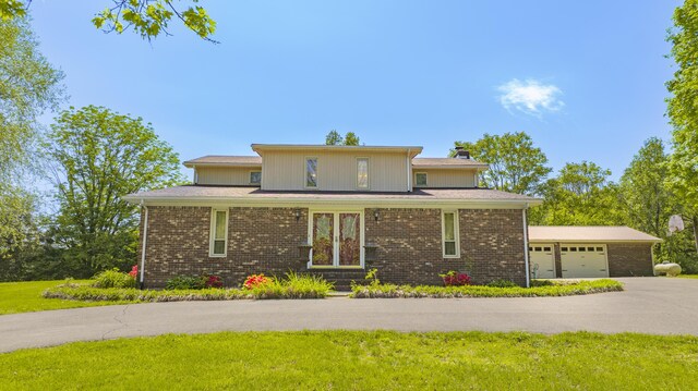 prairie-style home with an attached garage, a front lawn, driveway, and brick siding