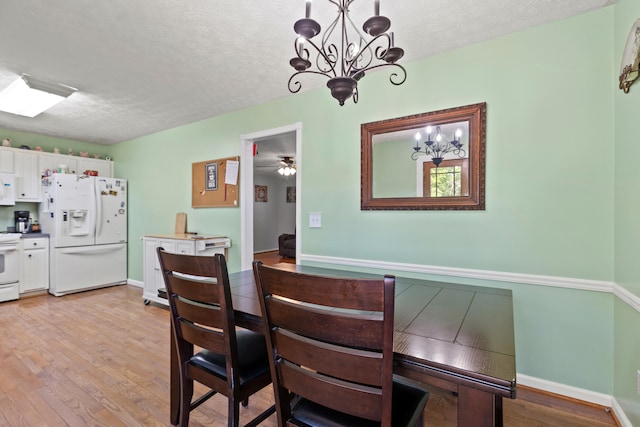 dining space with baseboards, a textured ceiling, a chandelier, and light wood-style flooring