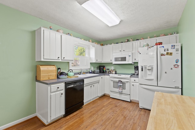 kitchen featuring a textured ceiling, light wood-style flooring, white cabinets, and white appliances