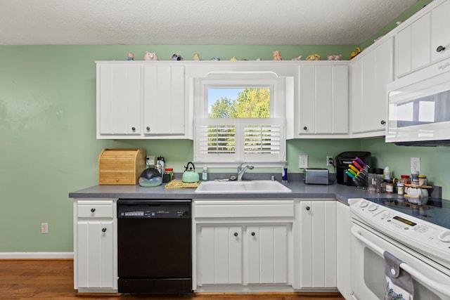kitchen featuring a sink, white appliances, a textured ceiling, white cabinetry, and wood finished floors
