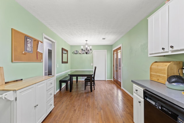 dining space with an inviting chandelier, baseboards, light wood finished floors, and a textured ceiling