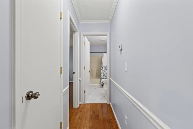 corridor featuring a textured ceiling, ornamental molding, and wood finished floors