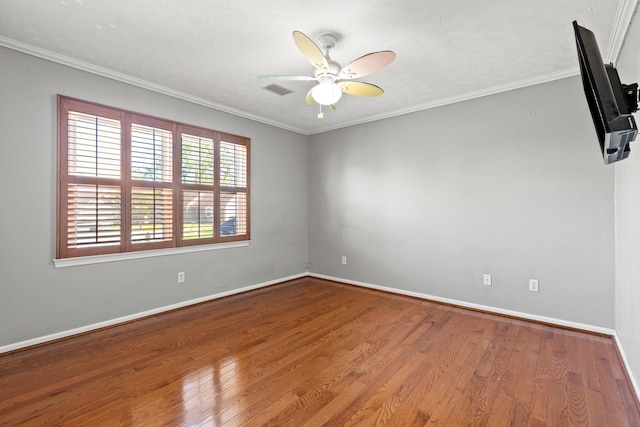 unfurnished room with a ceiling fan, visible vents, wood finished floors, baseboards, and ornamental molding