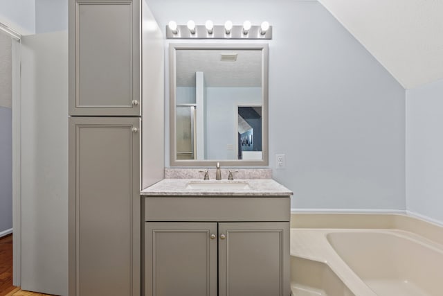 full bath featuring a textured ceiling, visible vents, a garden tub, and vanity