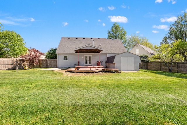 back of house featuring french doors, a storage shed, a deck, a lawn, and a fenced backyard