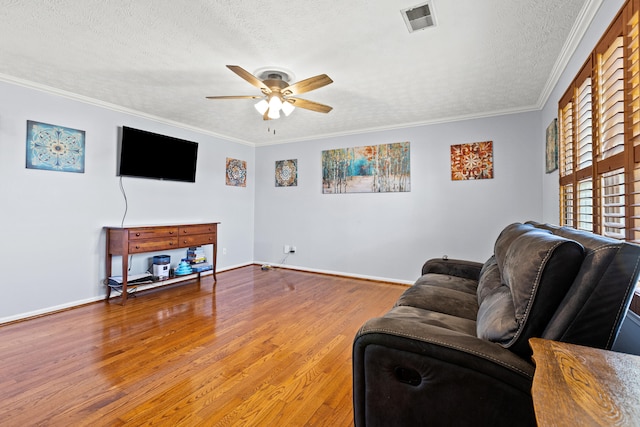 living room with ceiling fan, a textured ceiling, visible vents, wood finished floors, and baseboards