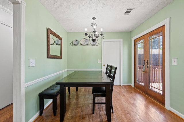 dining room featuring french doors, visible vents, hardwood / wood-style flooring, baseboards, and a notable chandelier