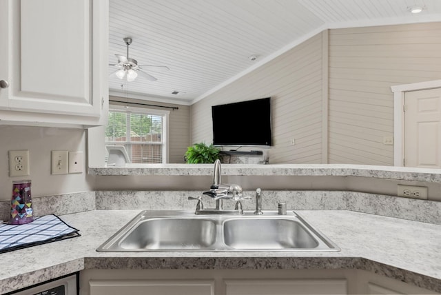 kitchen with ornamental molding, ceiling fan, light countertops, white cabinetry, and a sink