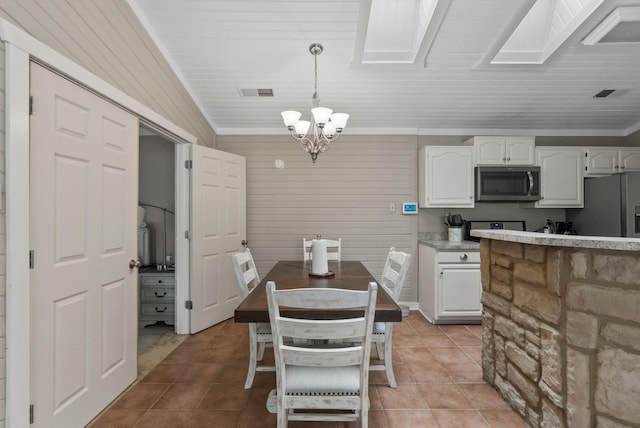 dining room with a notable chandelier, lofted ceiling with skylight, light tile patterned floors, and visible vents