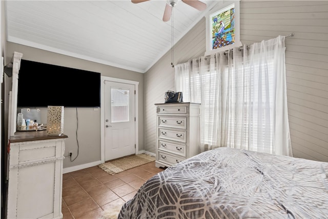 bedroom with light tile patterned floors, a ceiling fan, wood walls, and lofted ceiling
