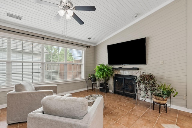 living room featuring ceiling fan, visible vents, light tile patterned floors, and lofted ceiling