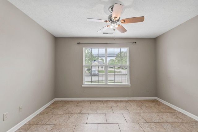 empty room with a textured ceiling, a ceiling fan, baseboards, light tile patterned floors, and visible vents