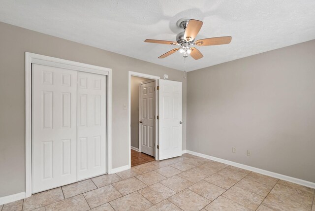 unfurnished bedroom featuring a closet, a ceiling fan, baseboards, and light tile patterned floors