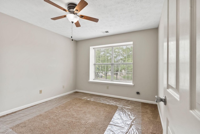 spare room featuring baseboards, a ceiling fan, a textured ceiling, and visible vents
